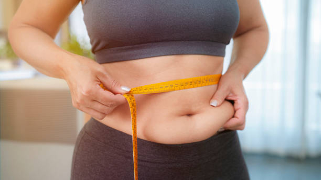 Plus size woman squeezing and measuring her waist